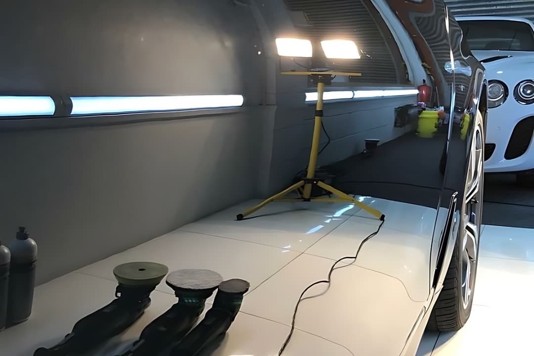 Pulidoras y el trípode de luz amarillo de K-WASH junto a un auto negro