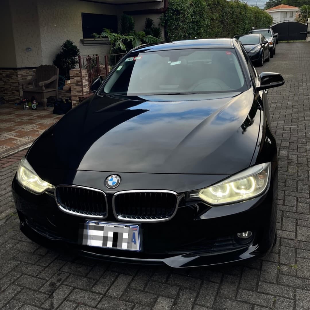 Frente del BMW 320i negro con los faros encendidos